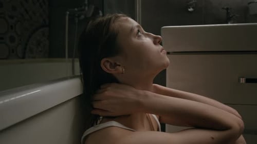 Close-up of Depressed Girl Putting Forehead on Knees Leaning against Bathtub