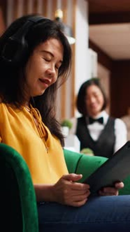 Vertical Video Asian Tourist Working on Tablet in Lounge Area at Resort