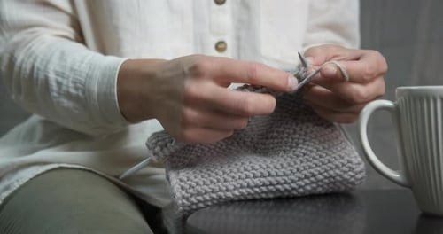 Woman Knitting a Grey Garment at Home