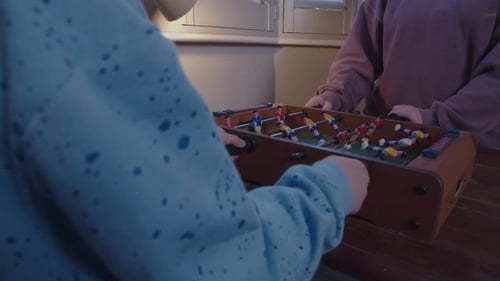 Kids play miniature table football.