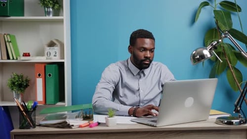 A Focused Professional is Diligently Working on a Laptop Within a Modern Office Space