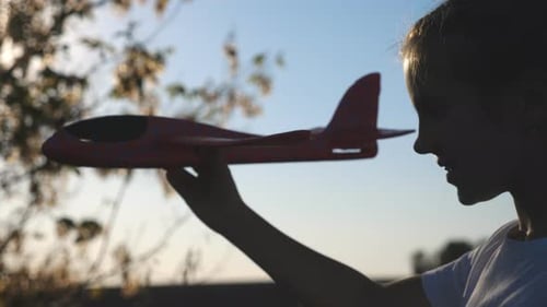 Girl Holds Toy Airplane at Sunset Time
