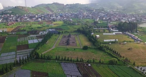 Orbit-Drohnenaufnahme des Arjuna-Tempelkomplexes auf dem Dieng-Plateau mit Hügeln und Siedlungen im Hintergrund.