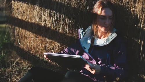 Woman uses laptop in rural sunny setting