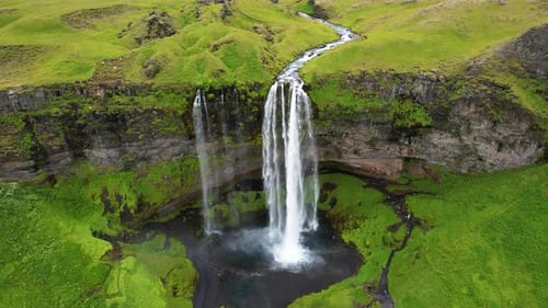 Breathtaking Aerial View Of Majestic Waterfall Cascading Down Green Cliffs