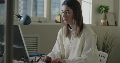 Ambitious Young Woman Working with Computer Typing Focused on Marketing at Desk in Office