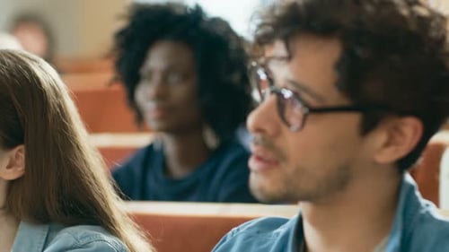 Im Klassenzimmer hören multiethnische Schüler einem Dozenten zu und schreiben in Notizbücher. Klug, jung