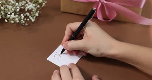 Hand Writes 'Thank You' Note with Gift