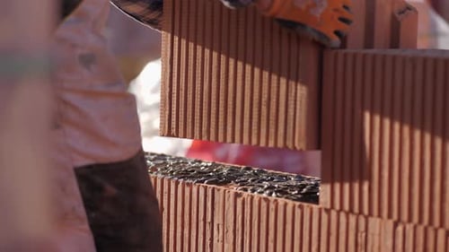 close-up of brick put in place on cement. worker man with big insulated brick being placed in the br