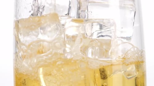 Close Up Of Beer Being Poured Into A Glass With Ice Cubes On The Light White Screen Background