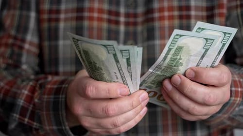 Close up men's hands counting cash, successful man in plaid shirt.