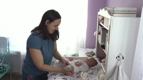 Young Mother Putting Woolen Socks on Her Baby