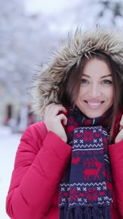 A Cheerful Woman in a Red Jacket and Fur Hood Beams in the Snow