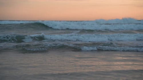 Sea Waves Against a Pink Sky in the Early Morning