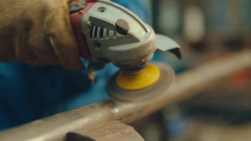 Metalsmith in Gloves Grinding Steel Pipe with Power Tool