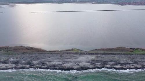 Blick aus der Vogelperspektive auf den Strand mit Sand, Gras und Steinen, die von der Bucht des Schwarzen Meeres und dem See unter dem Himmel umspült werden