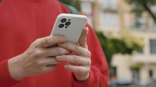 CloseUp Male Hands of Guy Texting Message on Mobile Phone Outdoors on Blurred Background Side View