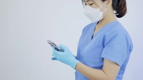 Close-up video of an Asian female doctor working on a smartphone chat.