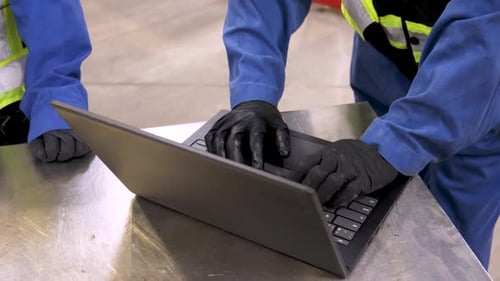 Mechaniker tippen auf Laptop in der Wartungseinrichtung, zwei afroamerikanische Männer arbeiten