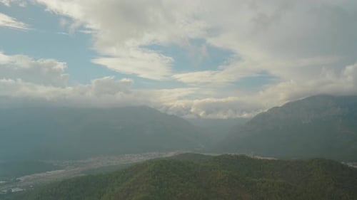Cinematic atmospheric sky from a high mountain with a view of the forest and the city nestled