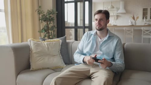 Young Man Plays Video Game on Couch