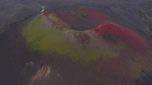 Luftaufnahme eines Vulkankraters mit roten und gelben Hängen in Island
