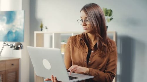 Smiling woman working on laptop in home office