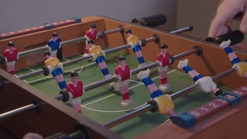 Children playing miniature table football, reset ball and score goal