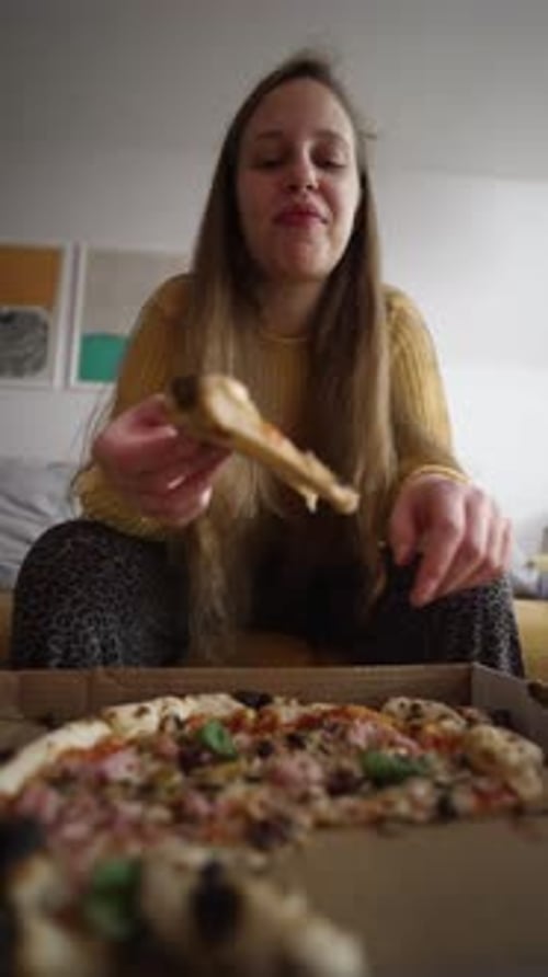 Young Woman Enjoys Pizza Slice at Home