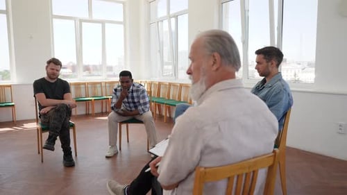 View From Back of Professional Mature Male Psychologist to Depressed Young Man Sharing Problem