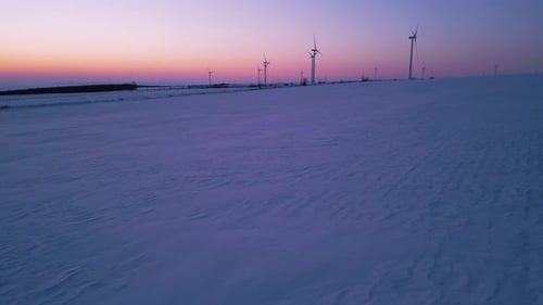 Wind Turbines on Snowy Field at Sunrise