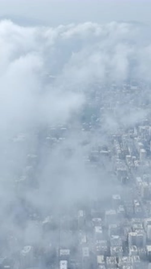 Vertical Video Heavy Grey Clouds Looming Over a City Before a Storm With Rooftops Below