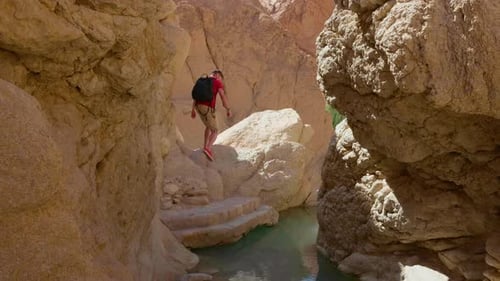 Man carefully passing the rocks in the river between high mountains.