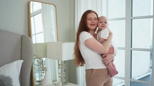 Loving Mother Holding Baby in Bright Bedroom