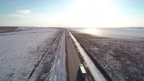 Aerial Shot of an Intercity Road with Traffic Surrounded with Snow Covered Fields Winter Landscape