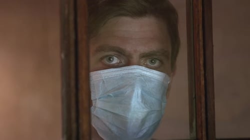 Close Up of Adult in Face Mask Behind Window