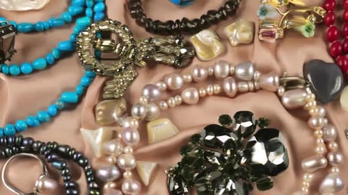 Bijoux en pierres précieuses et perles sur fond de soie beige sous l'eau.