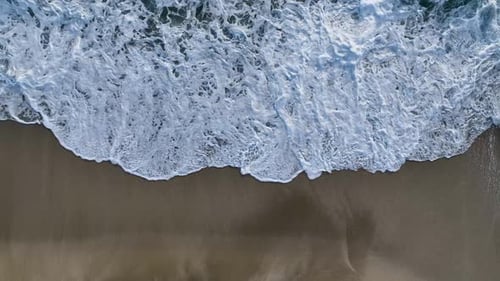 Cinematic Top Down Abstract Aerial View of Ocean Waves Crashing on Rocky Shoreline
