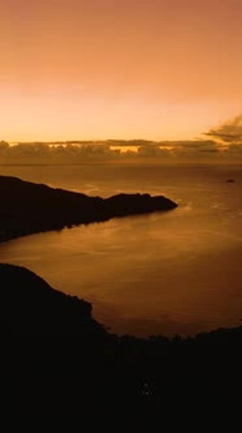 Des teintes dorées s'étendent sur le ciel et les eaux calmes au crépuscule Praslin Seychelles