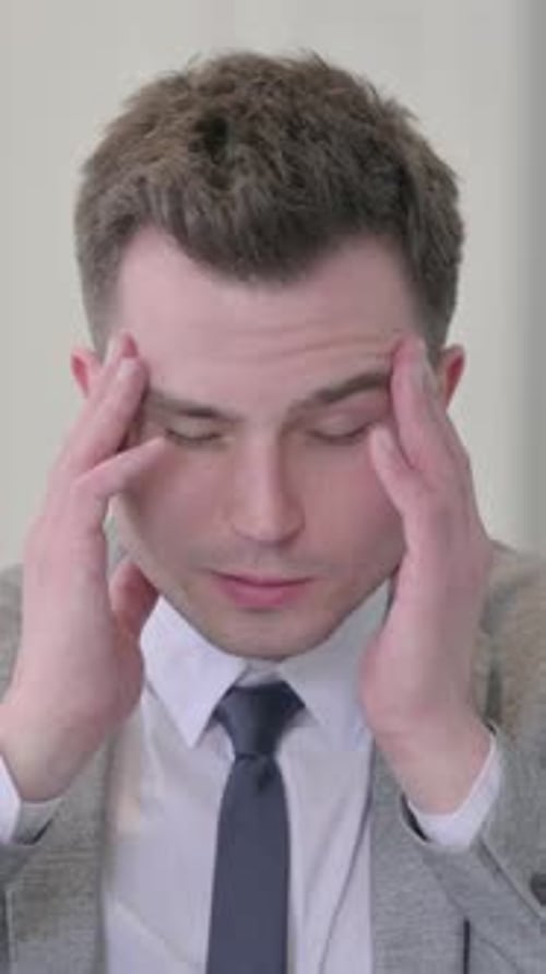 Stressed Young Man Massaging Temples in Close Up