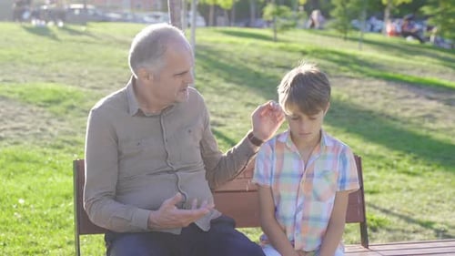 Grandfather and Boy Chatting on Park Bench
