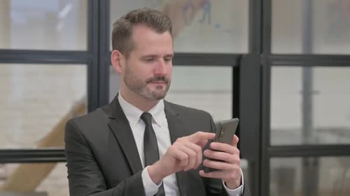 Businessman Using Smartphone in Modern Office Setting