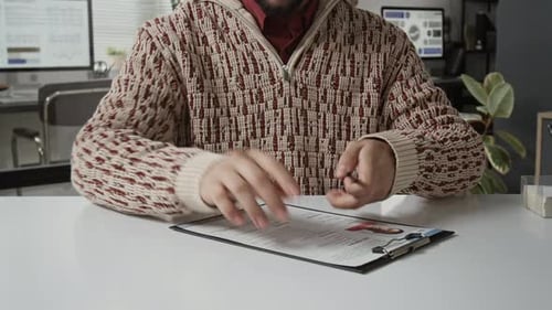 Midsection of Man Signing Application Form Attached to Clipboard and Showing It