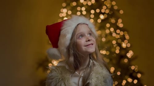 Happy Child Wearing Santa Hat In Front Of Tree