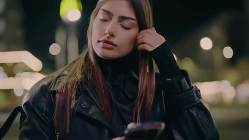 Closeup of a Woman Holding and Using Her Phone While Standing in the City