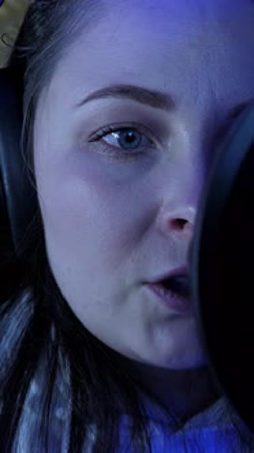 Portrait of woman singer in headphones singing into microphone. Vertical video