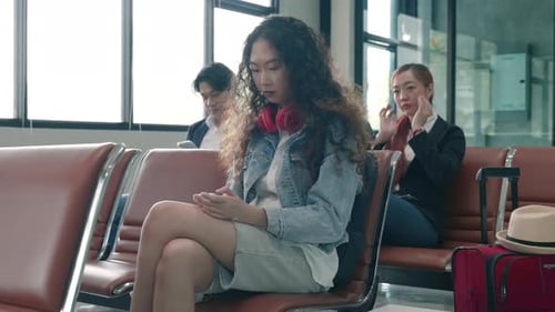 Passenger traveler woman in airport gate play smartphone for waiting air vacation travel