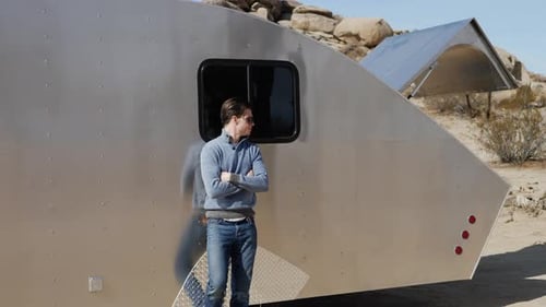 Man Standing Near Trailer in Desert Landscape