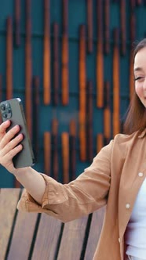 Close Up of Pretty Caucasian Girl Talking on Video Call Using Phone Outdoors While Sitting on Bench