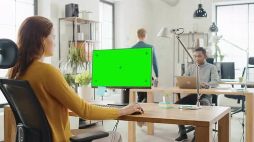 Woman at Computer with Chroma Key Screen in Office